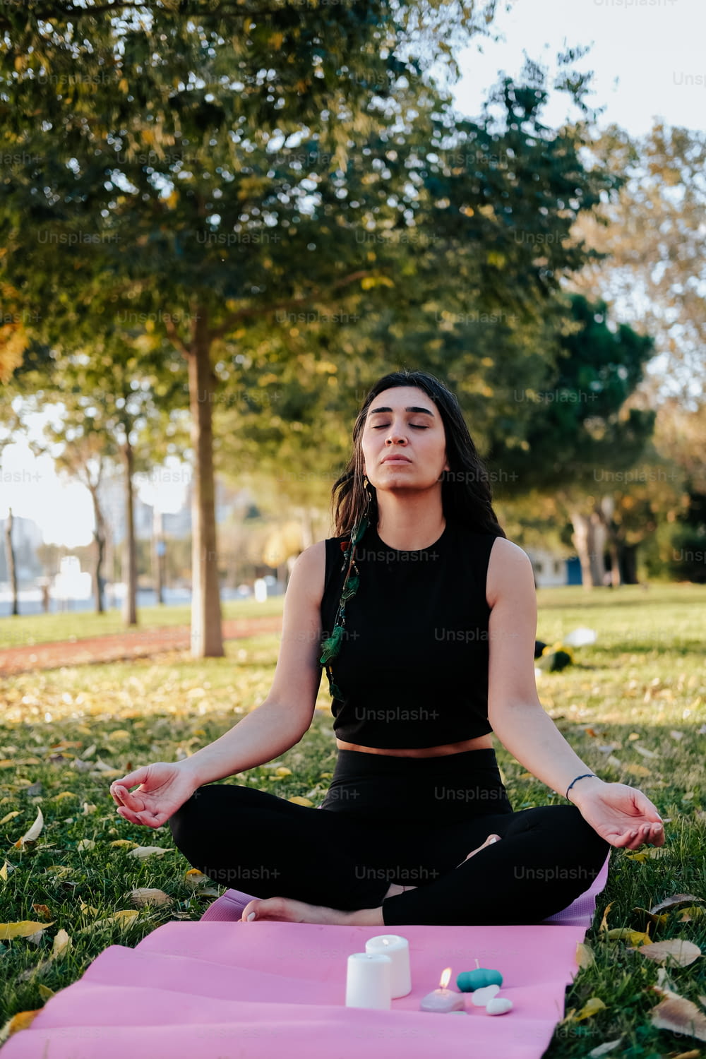 Una mujer sentada en una posición de yoga en un parque
