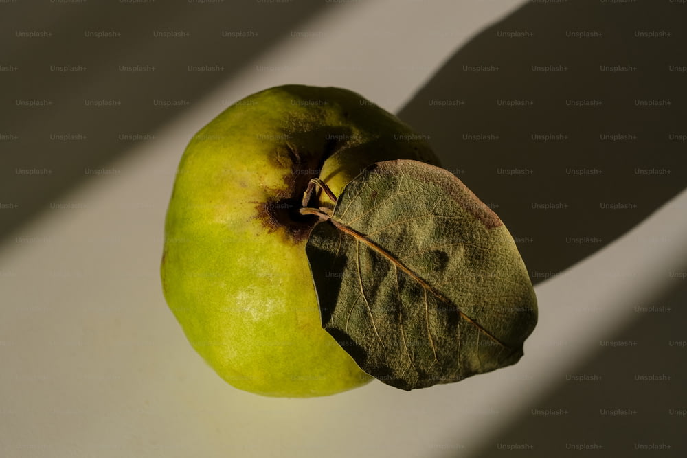 a green apple sitting on top of a white table