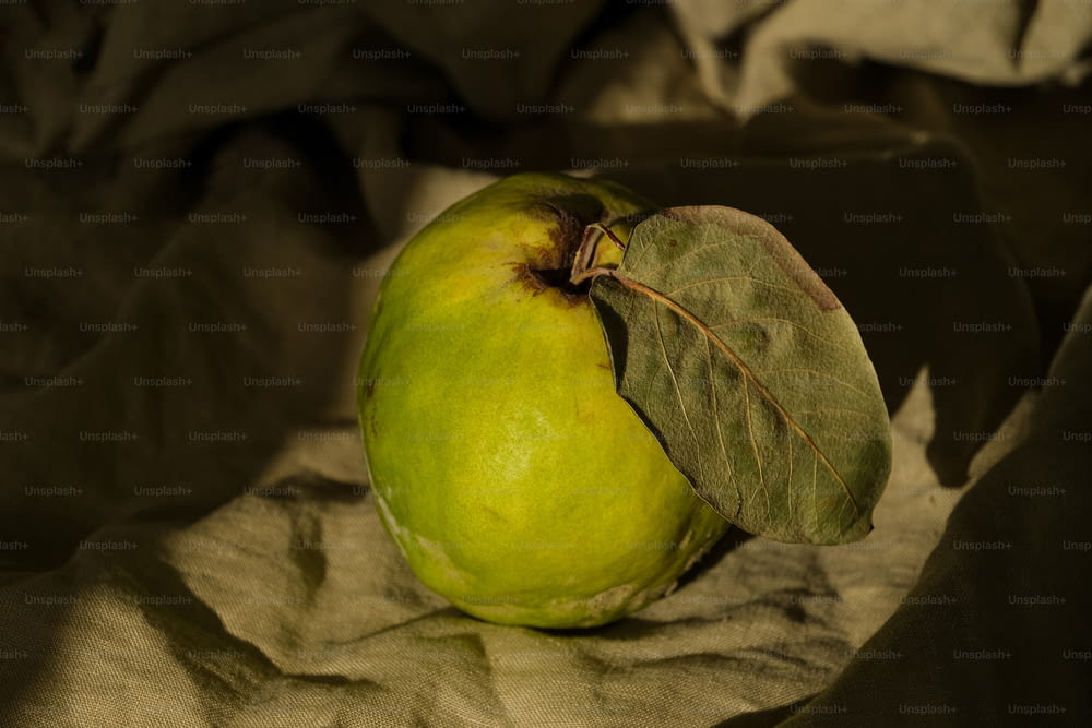 una manzana verde con una hoja encima