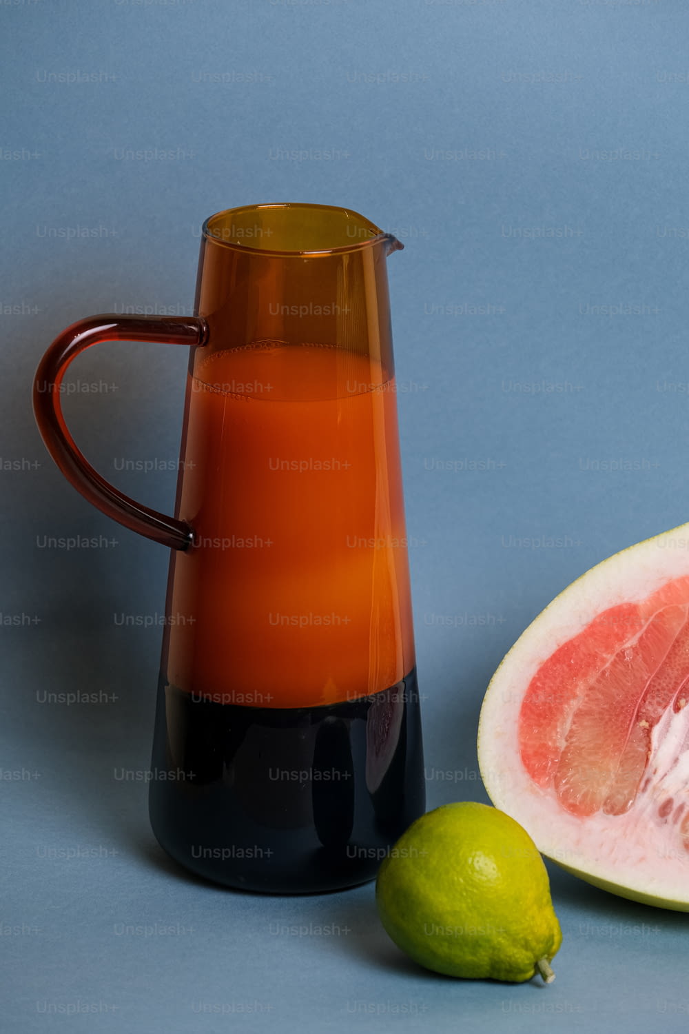a pitcher of liquid next to a half of a grapefruit