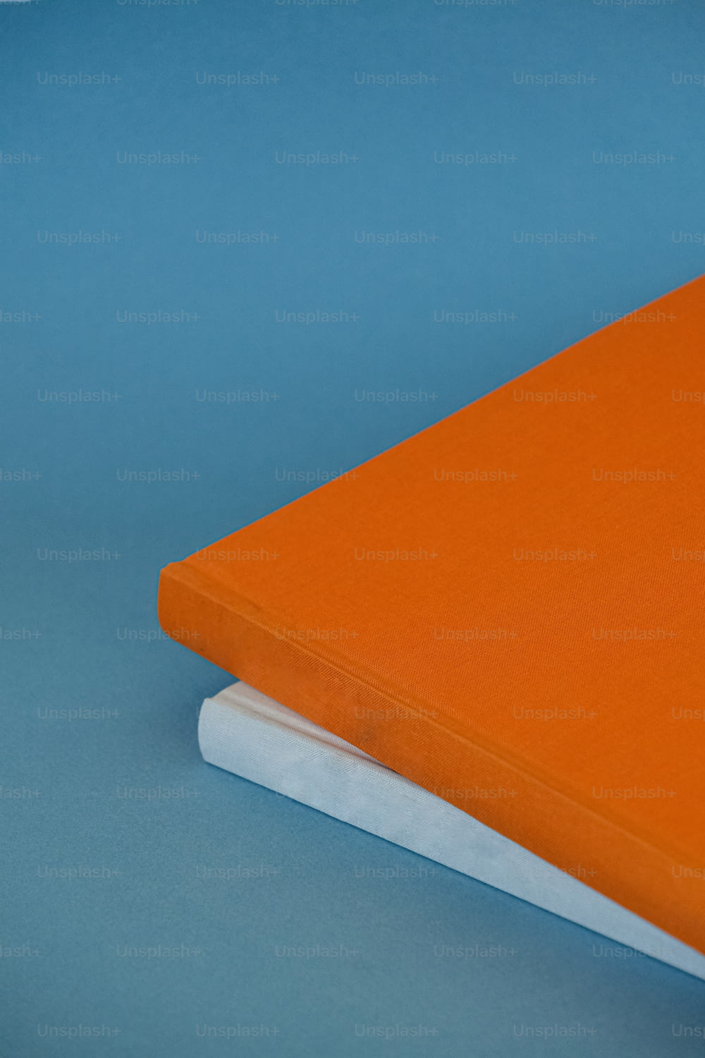 an orange notebook sitting on top of a white book