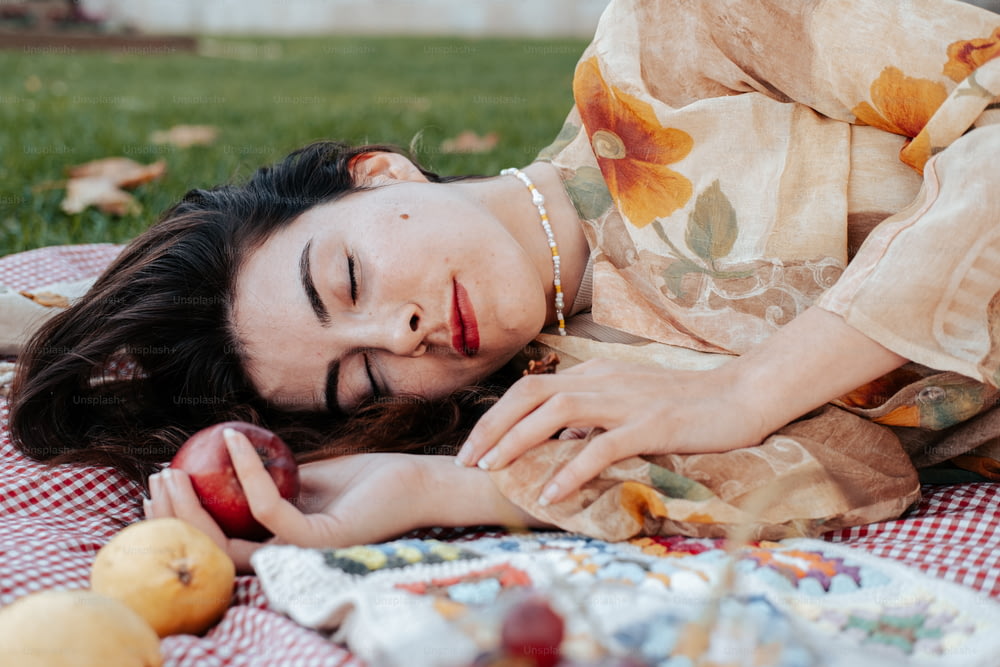 Una mujer acostada sobre una manta sosteniendo una manzana