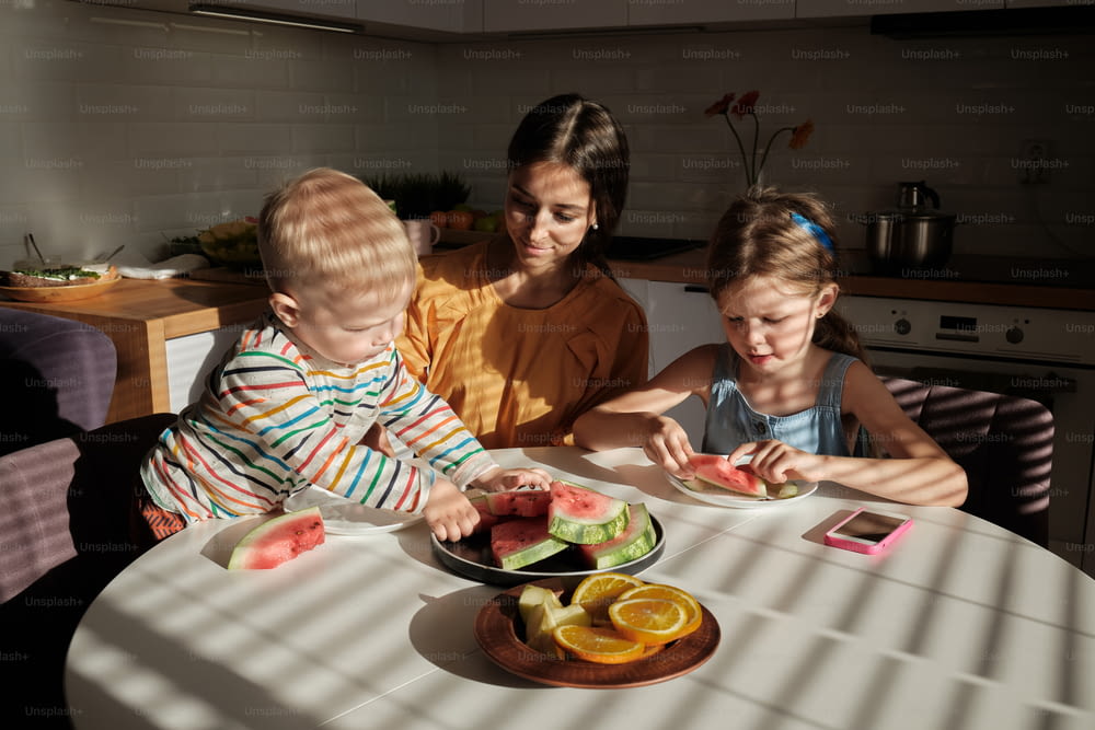 un groupe d’enfants assis autour d’une table en train de manger de la nourriture