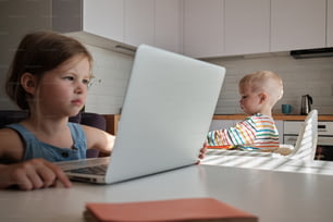 a young child sitting at a table using a laptop computer