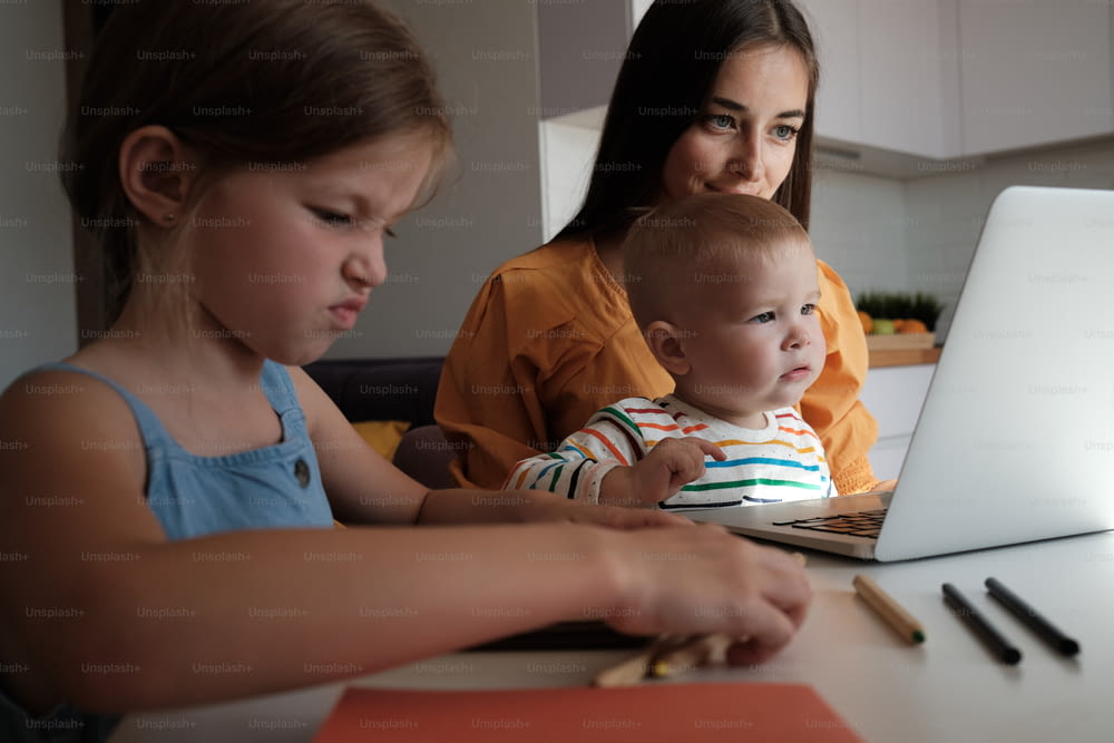 a woman and a child sitting in front of a laptop computer