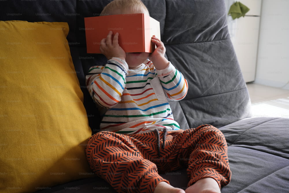 un ragazzino seduto su un divano che tiene in mano un libro
