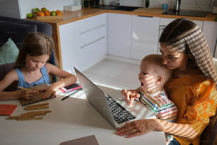 Une femme et deux enfants assis à une table avec un ordinateur portable