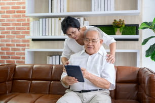 Un couple asiatique âgé heureux utilise une tablette et parle avec sa famille sur webcam à la maison, concept de retraite.