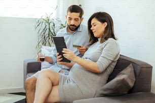 Couple adulte attendant bébé shopping en ligne à la maison.