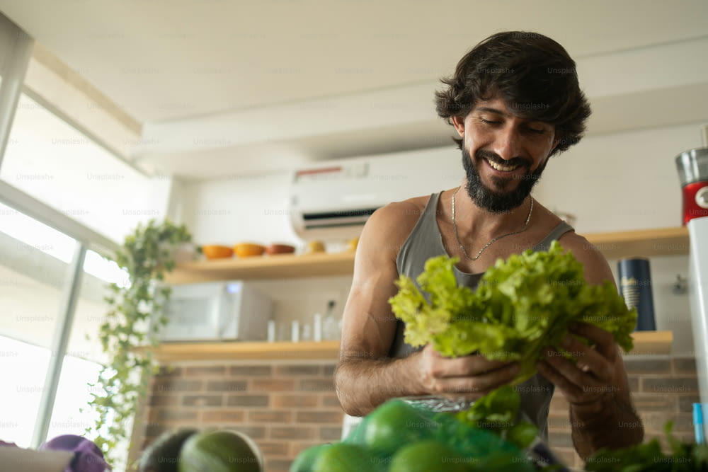 Happy and healthy young man meal prepping whole vegetarian meal in the kitchen. High quality photo. Feel good, healthy and health concept.