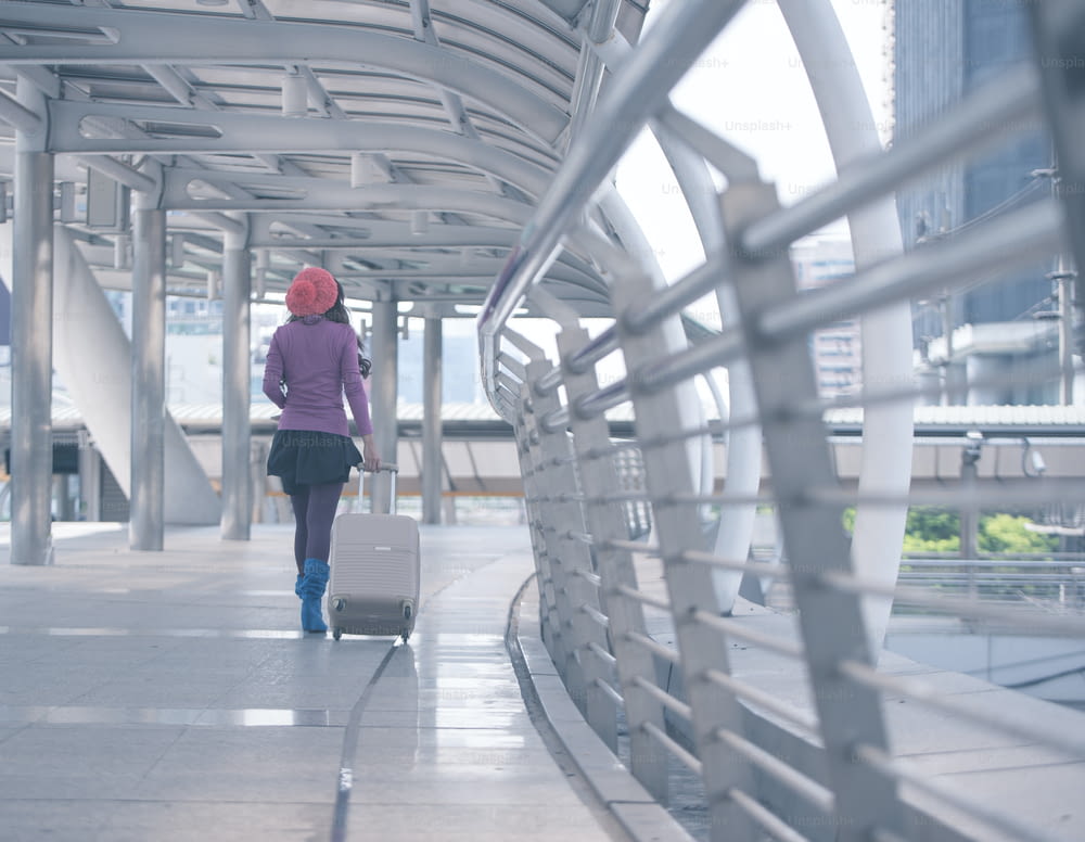 vista traseira mulher viajante andando com mala no corredor do aeroporto