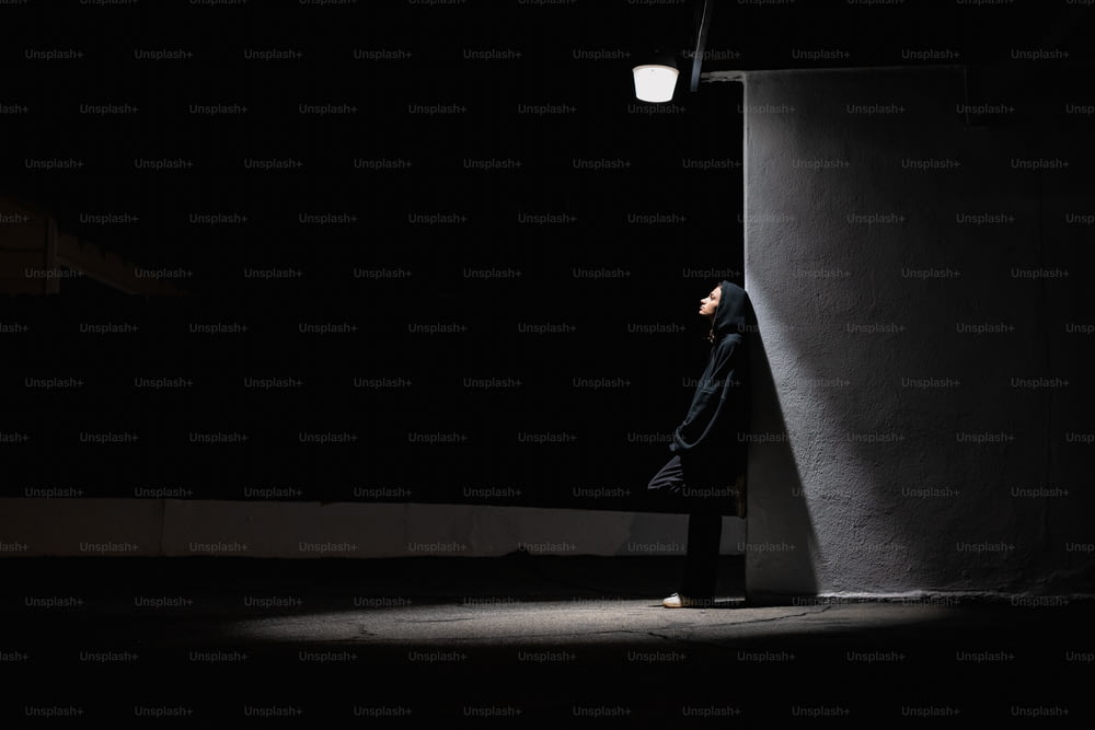a man leaning against a wall in the dark