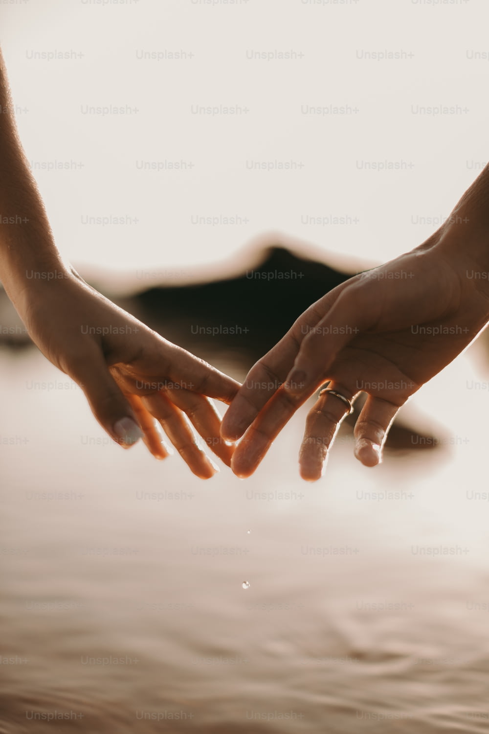 Zwei Personen, die sich über einem Gewässer an den Händen halten