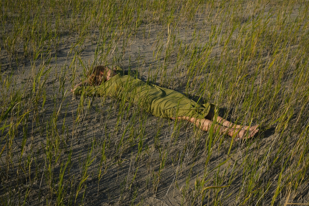 uma pessoa deitada em um campo de grama alta