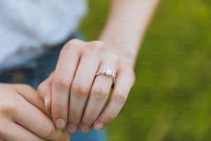 um close up de uma pessoa segurando um anel de diamante