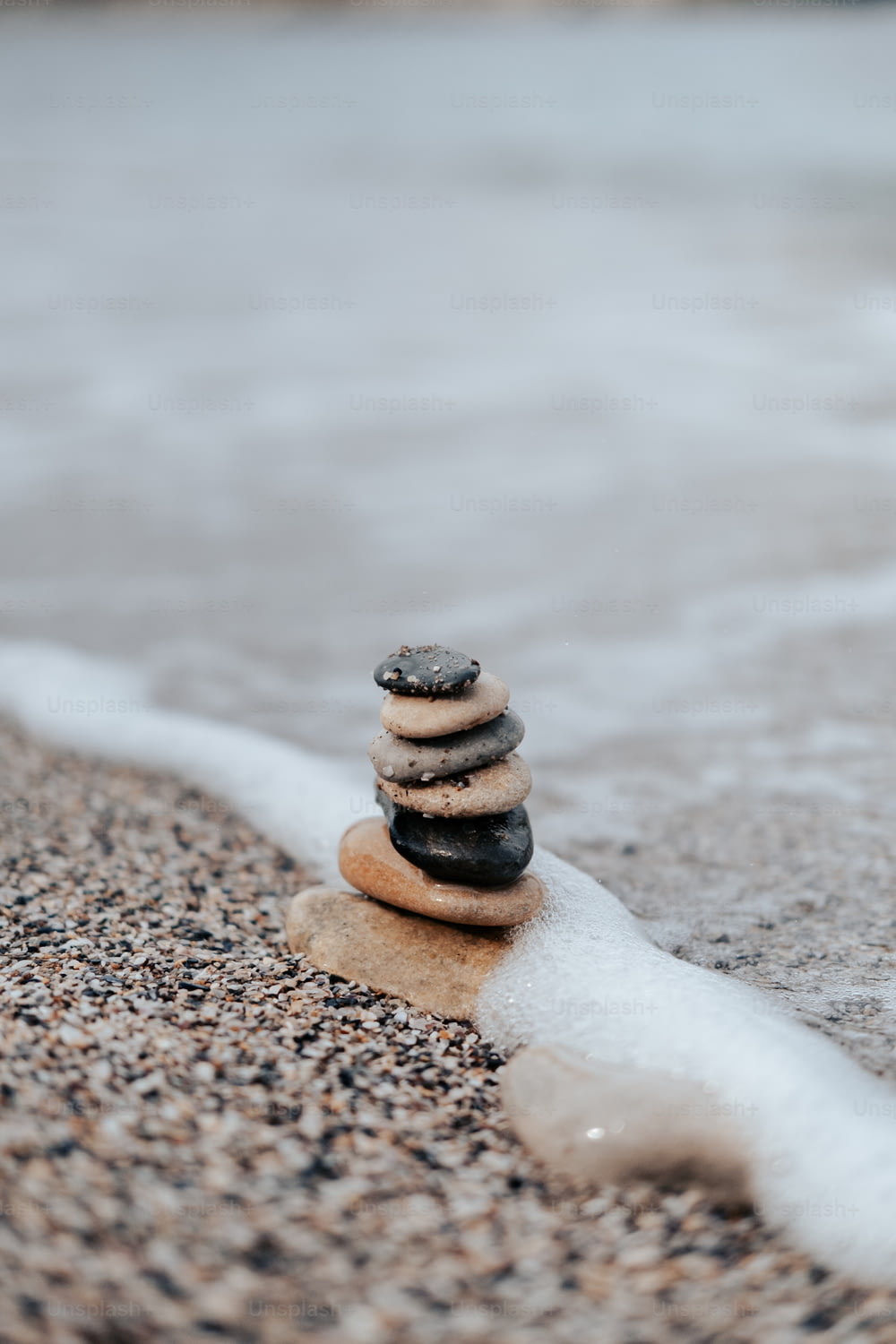 Ein Stapel Felsen, der auf einem Sandstrand sitzt