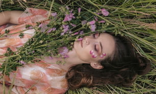 uma mulher deitada na grama com flores ao seu redor