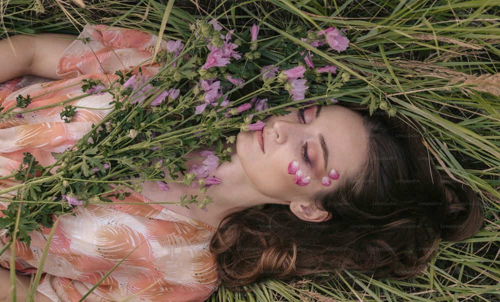 a woman laying in the grass with flowers around her
