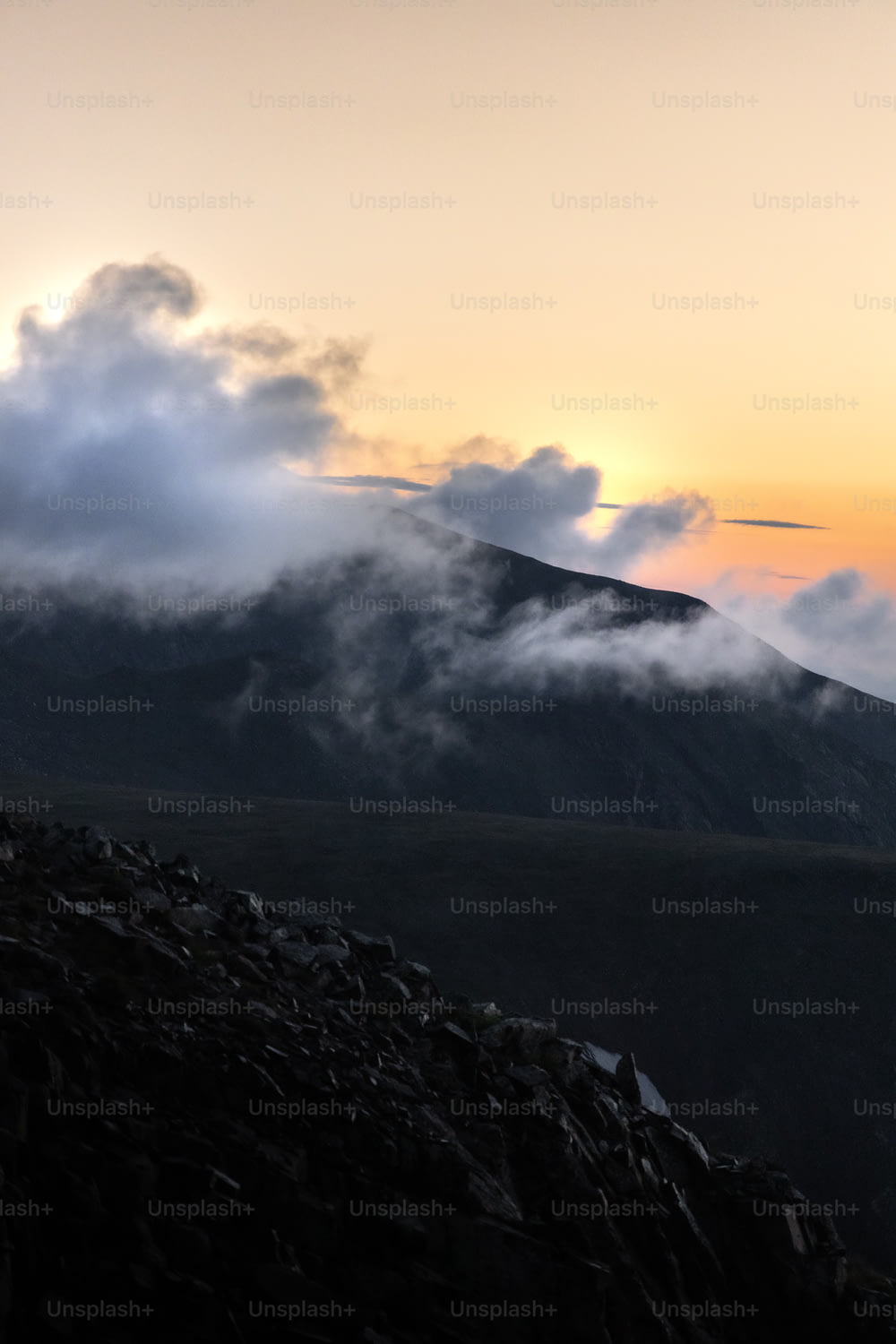 a mountain covered in clouds at sunset