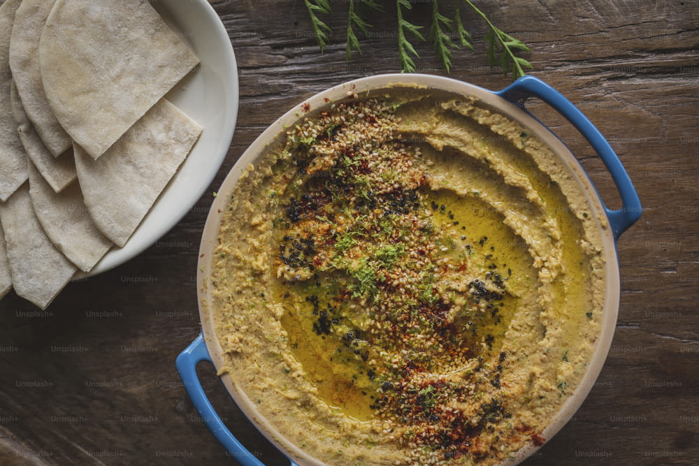 a bowl of hummus and pita chips on a wooden table