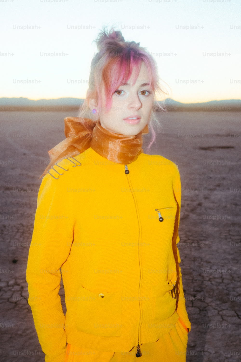 a woman with pink hair wearing a yellow jacket