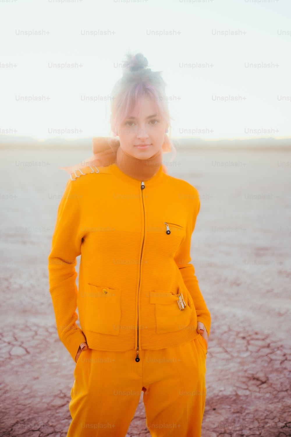 a woman in a yellow suit standing in a desert