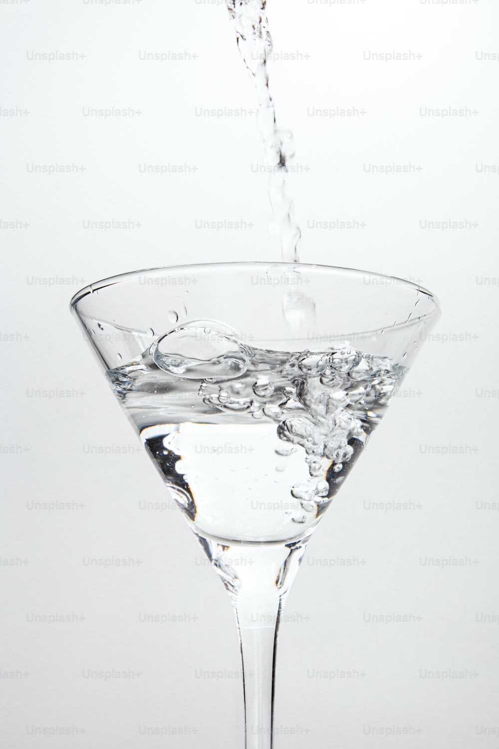 Un bicchiere da martini riempito d'acqua su uno sfondo bianco