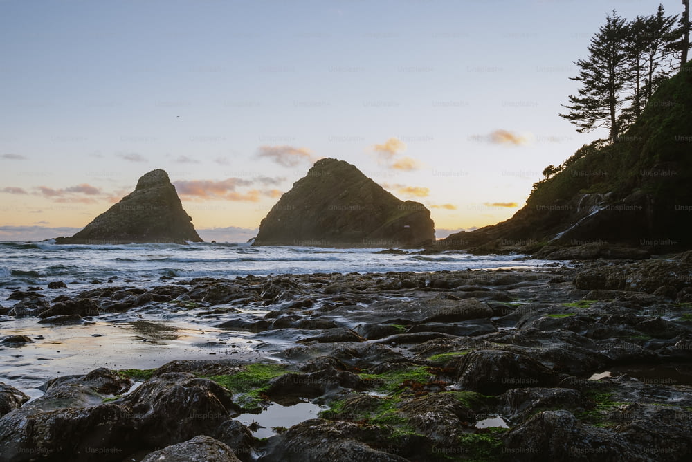 Una spiaggia rocciosa con un paio di grandi rocce sullo sfondo