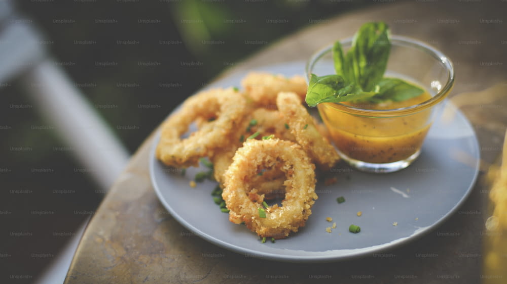 a plate with onion rings and dipping sauce