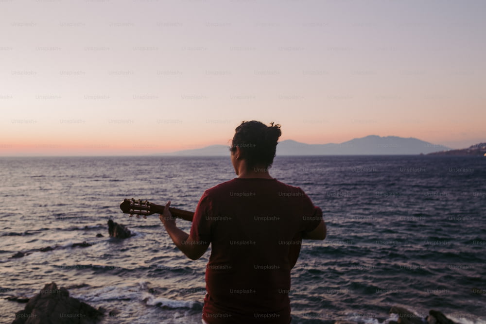 a man playing a guitar on the beach