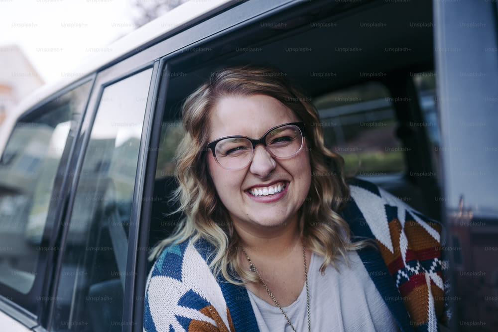 a woman wearing glasses sitting in a car
