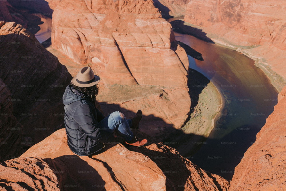 Ein Mann, der auf einer Klippe neben einem Fluss sitzt