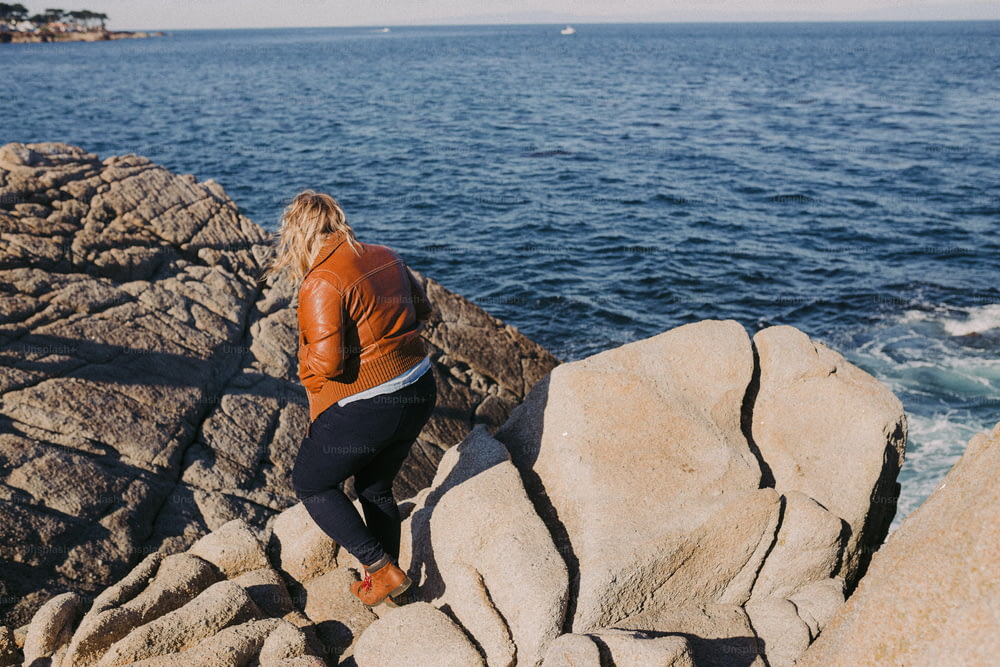 Una donna seduta su una roccia vicino all'oceano
