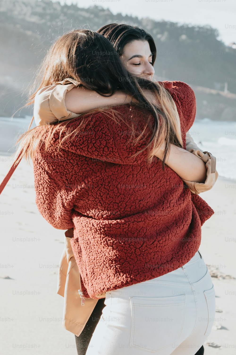 a woman is hugging another woman on the beach