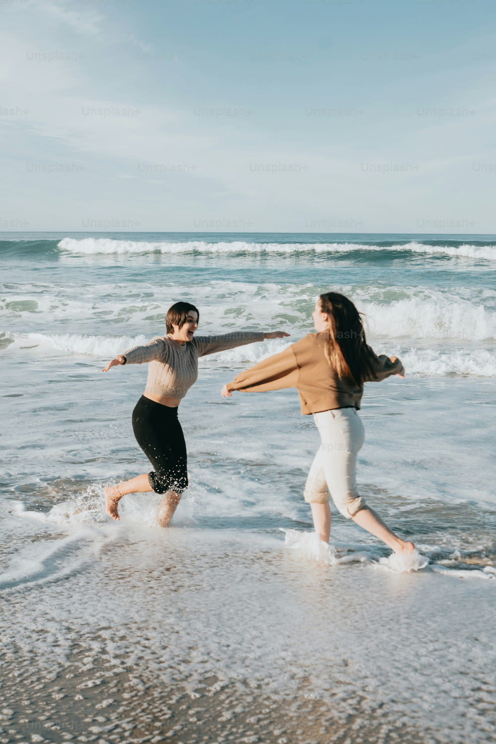 two women running in the water at the beach