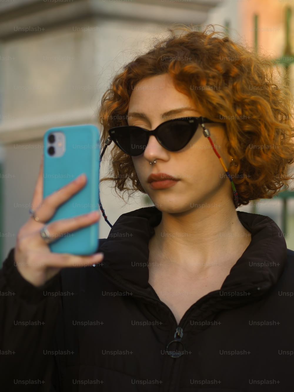 赤い髪とサングラスをかけた女性が携帯電話を持つ