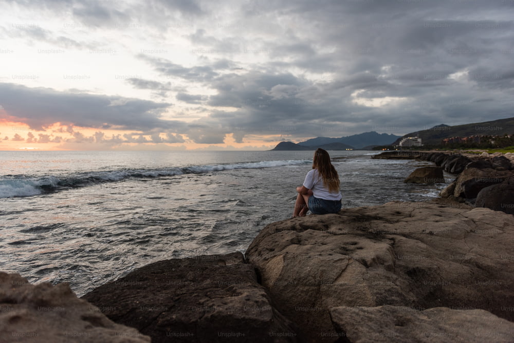 une personne assise sur un rocher au bord de l’eau