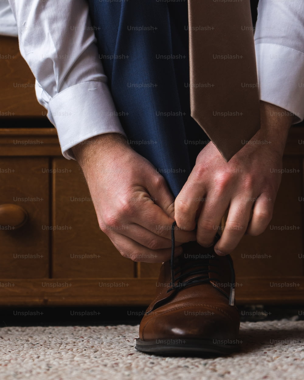 a man tying a tie on a brown shoe