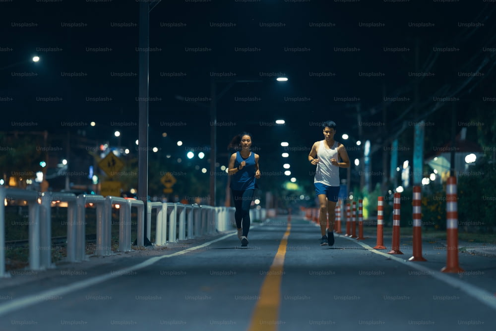 Asian couple jogging in the city streets at night