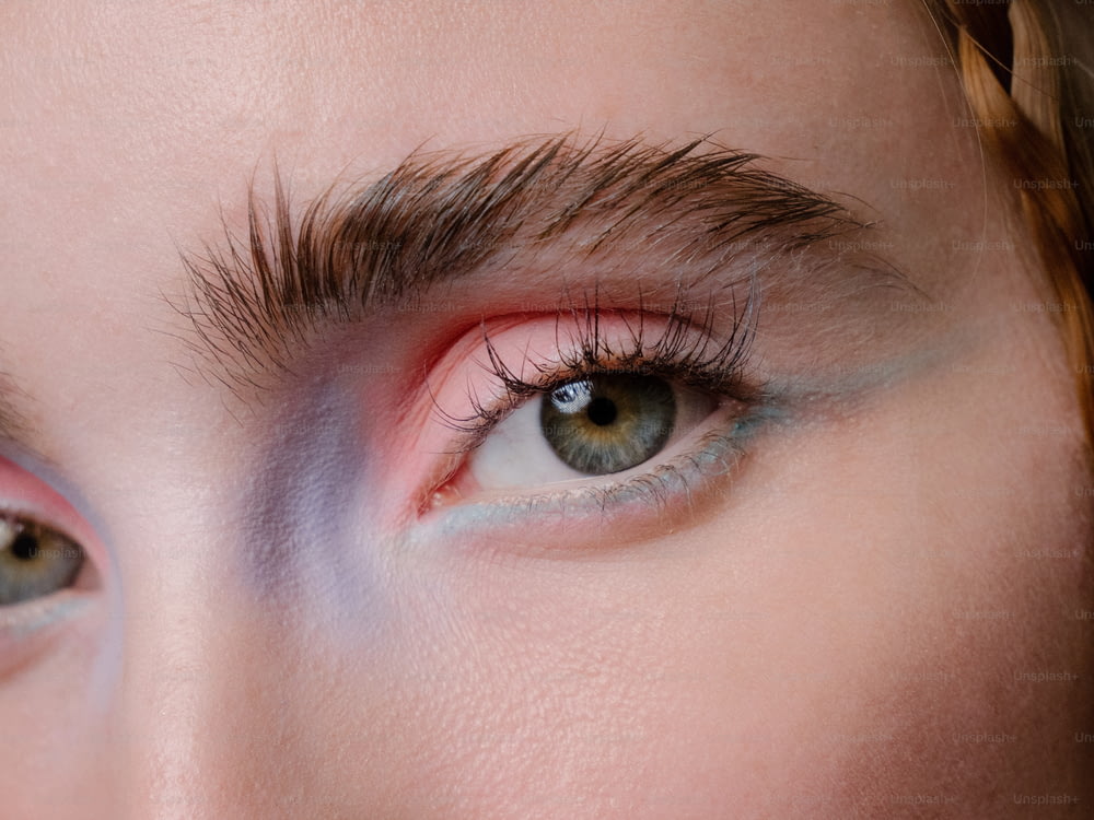 a close up of a woman's eye with pink and blue makeup