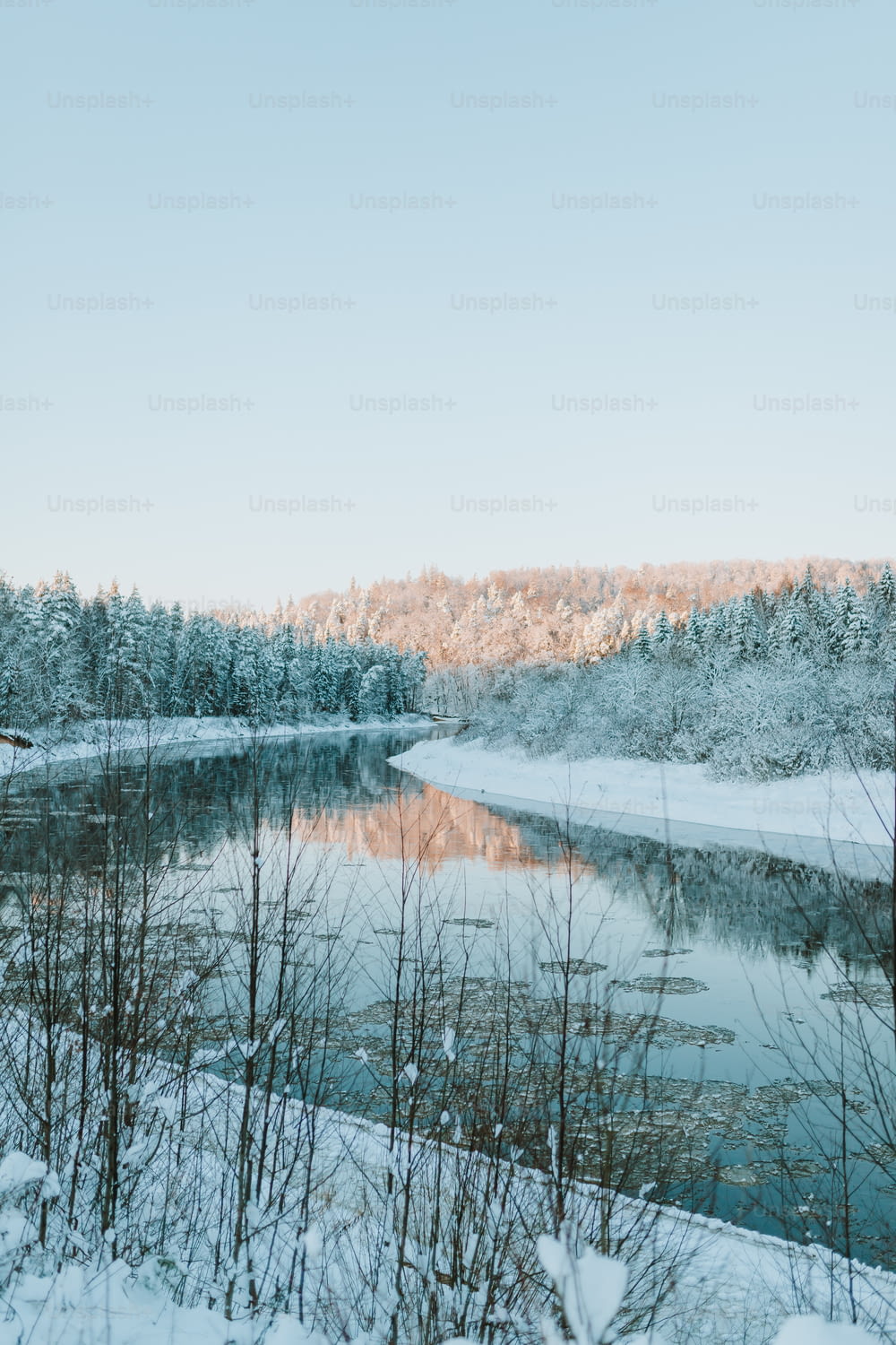 a lake surrounded by snow covered trees and a forest