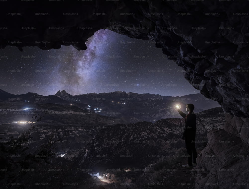 a person standing in a cave looking at the stars