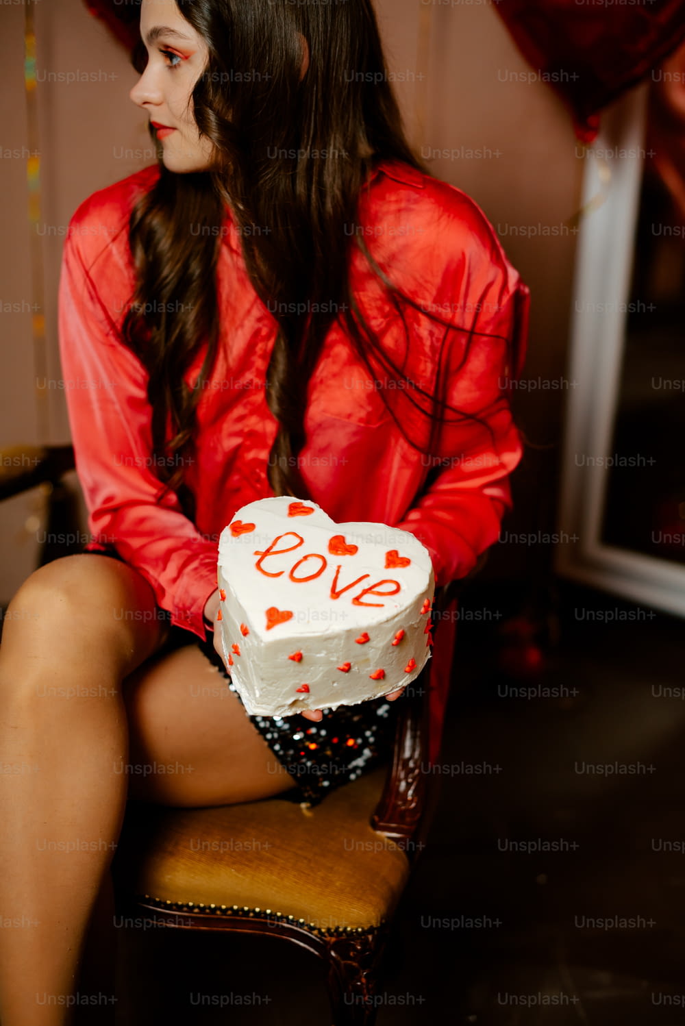 a woman sitting on a chair with a cake in front of her
