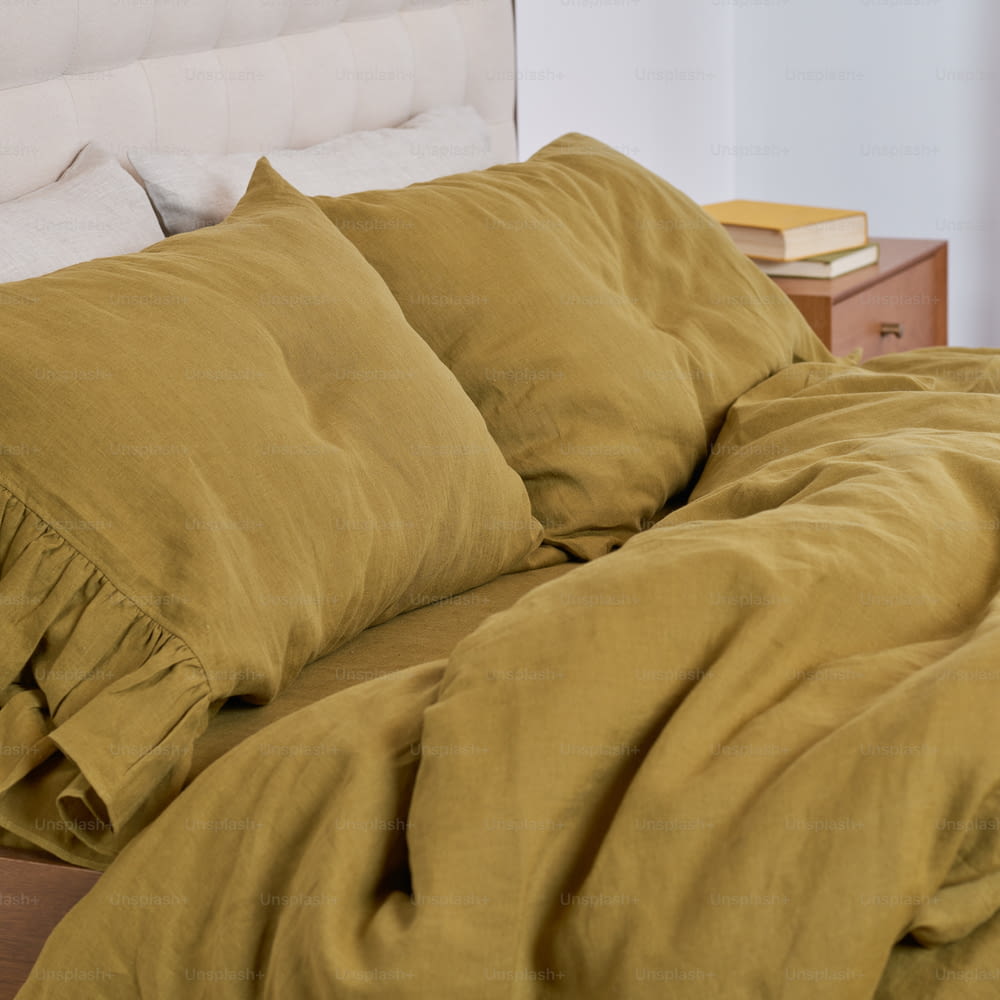 a bed with a yellow comforter and a white headboard