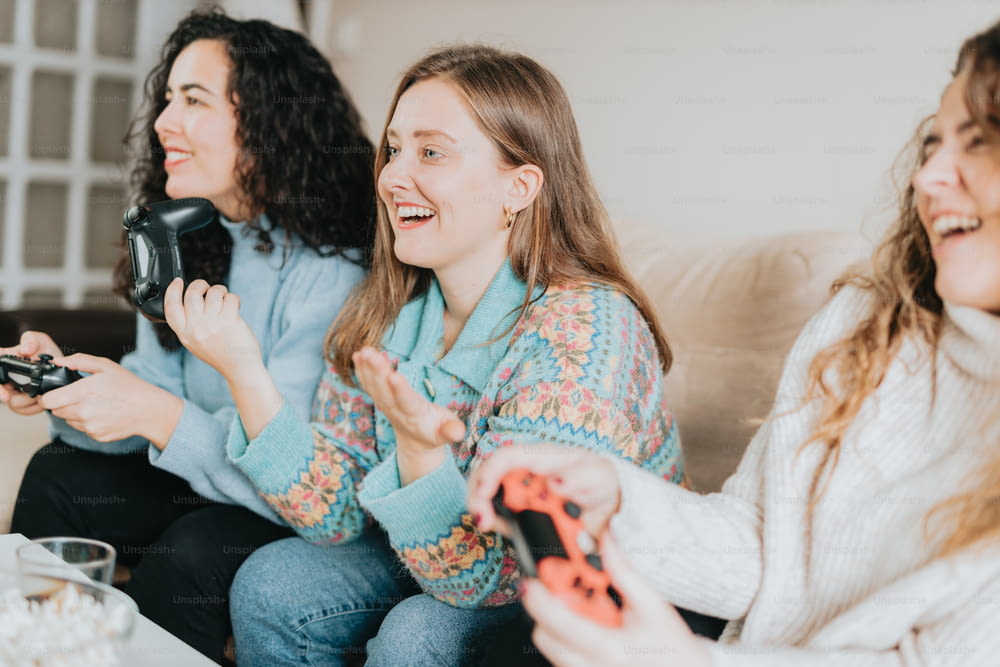 three women sitting on a couch playing a video game