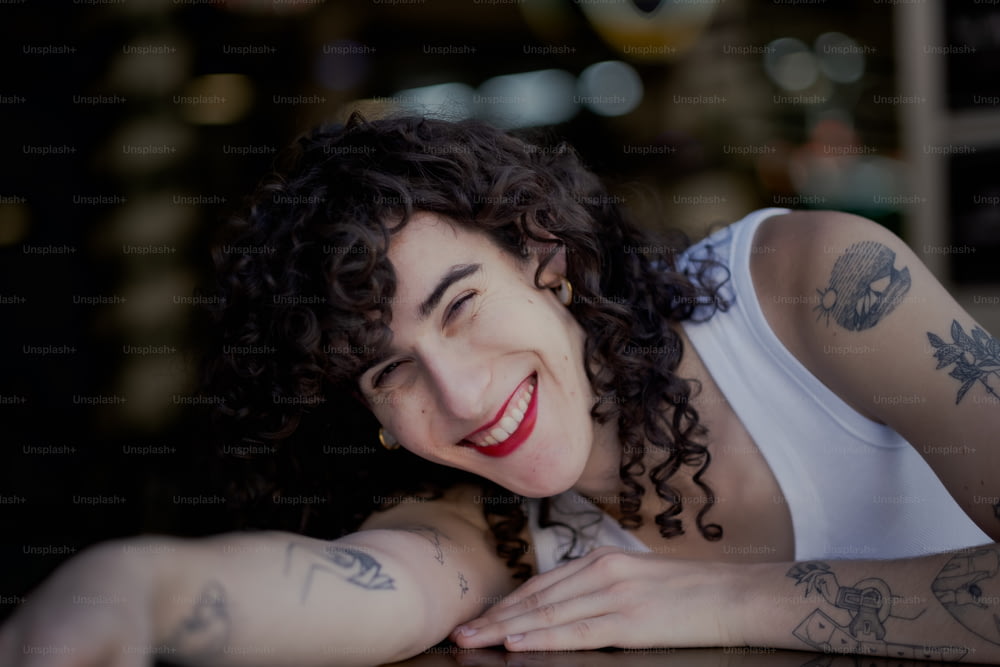 Una mujer sonriente con tatuajes en los brazos