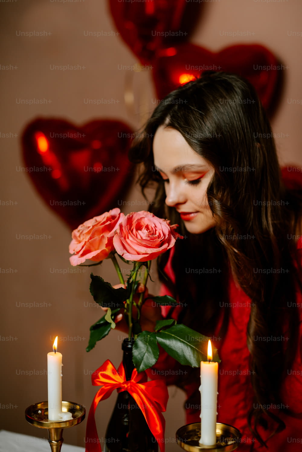 a woman in a red dress smelling a rose