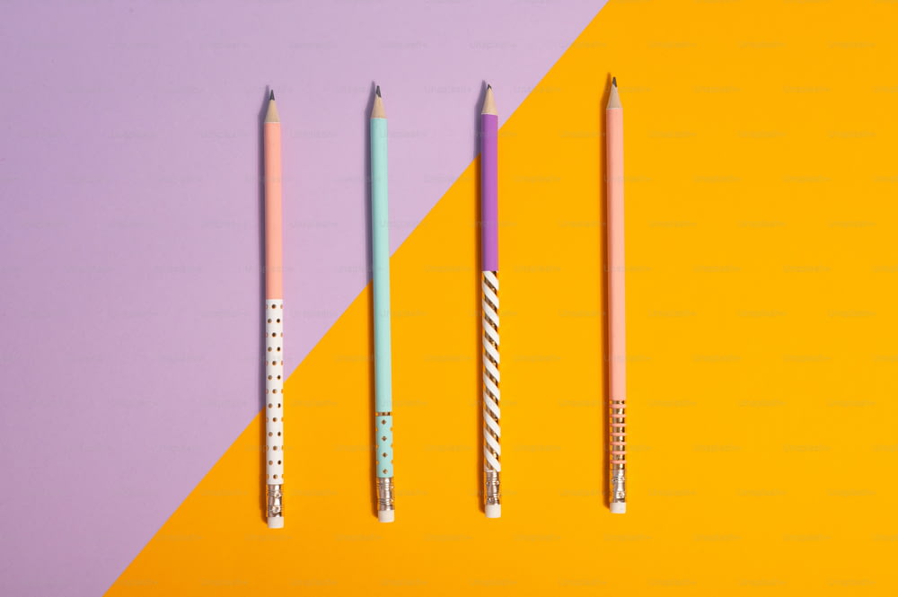 Tre matite allineate su sfondo giallo e viola