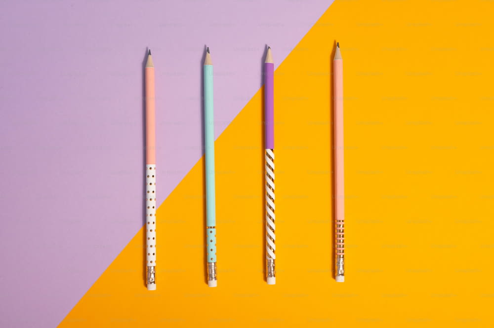 Trois crayons alignés sur un fond jaune et violet