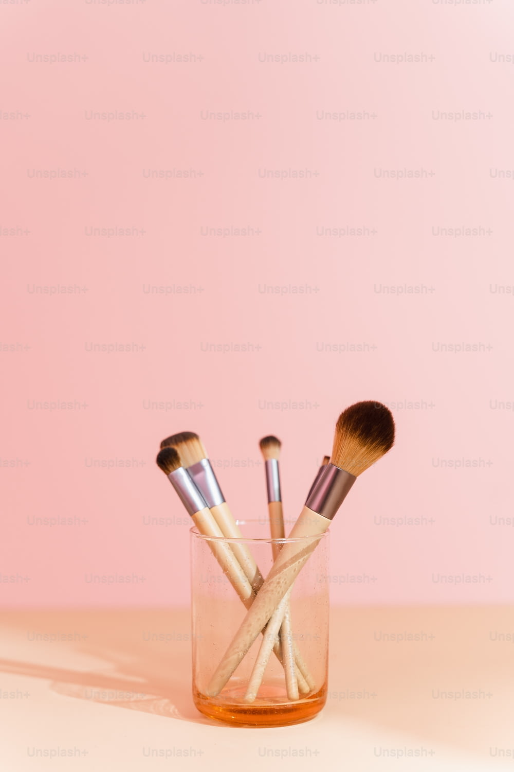 a glass filled with makeup brushes on top of a table